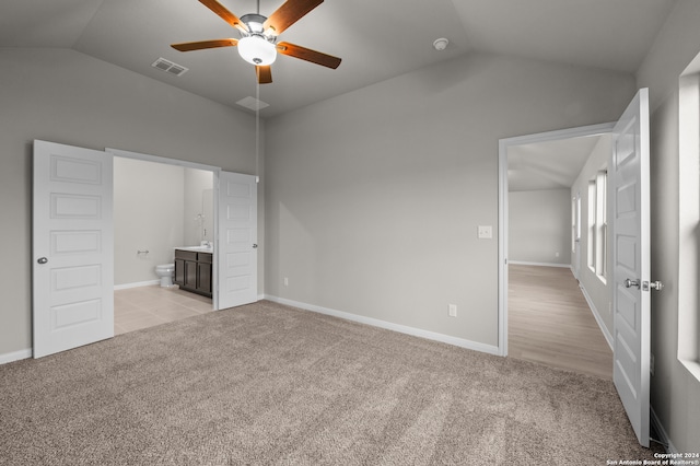 unfurnished bedroom featuring light carpet, ceiling fan, ensuite bath, and lofted ceiling