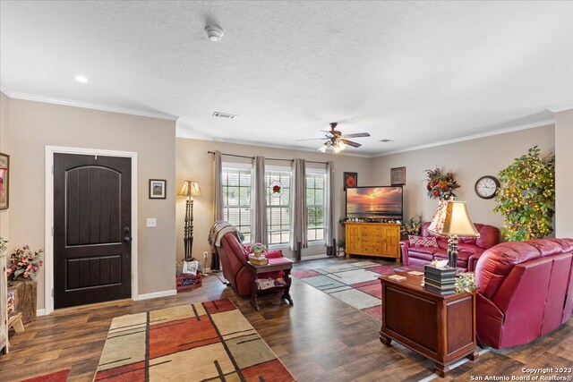 living area with crown molding, visible vents, a textured ceiling, wood finished floors, and baseboards