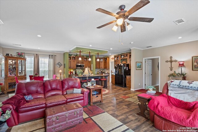 living area with visible vents, a ceiling fan, ornamental molding, dark wood-style flooring, and recessed lighting