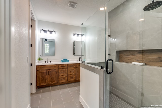 bathroom with tile patterned flooring, a textured ceiling, vanity, and walk in shower