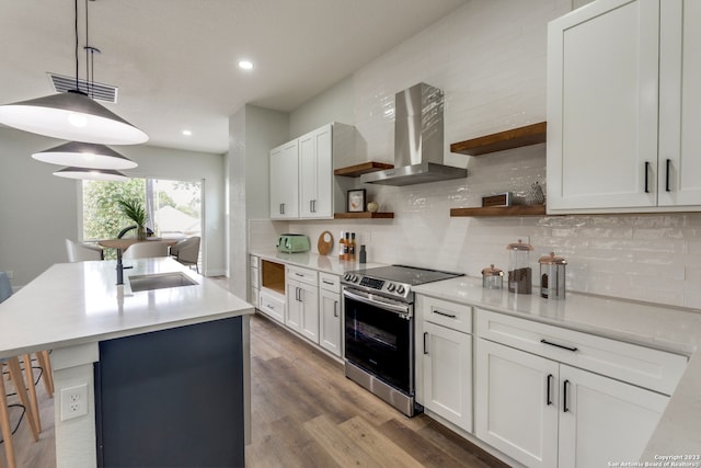 kitchen with stainless steel electric stove, white cabinets, decorative light fixtures, and wall chimney range hood