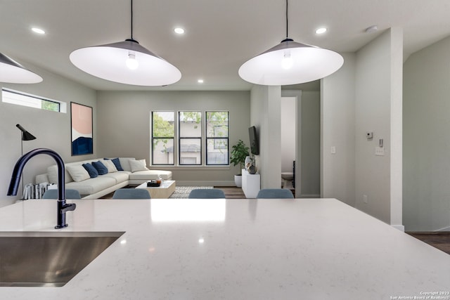 kitchen featuring light stone counters, sink, a healthy amount of sunlight, and decorative light fixtures