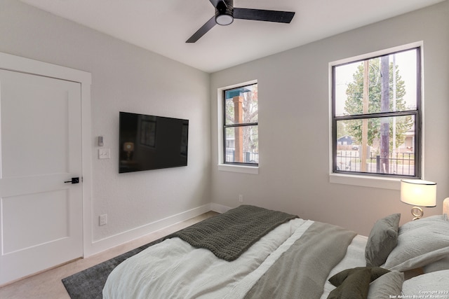 bedroom featuring ceiling fan, light carpet, and multiple windows