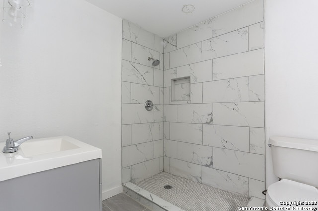 bathroom featuring vanity, toilet, and tiled shower