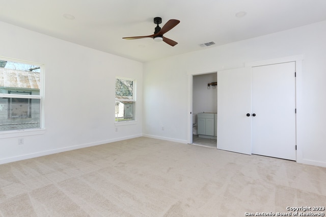 carpeted empty room with a healthy amount of sunlight and ceiling fan