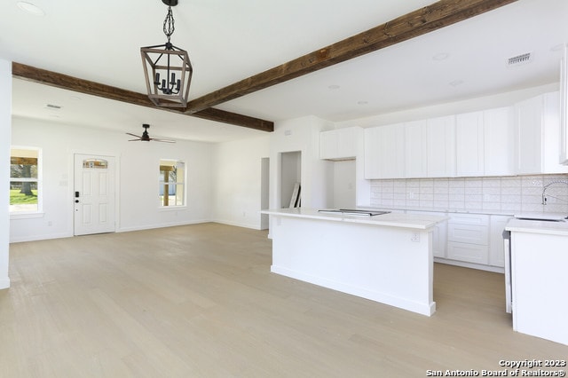 kitchen with a kitchen island, ceiling fan, tasteful backsplash, white cabinets, and light wood-type flooring