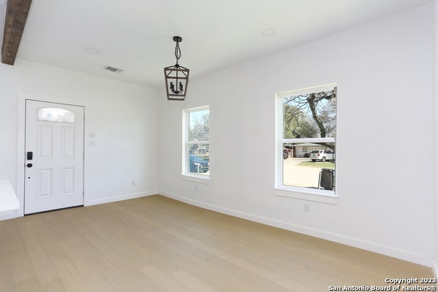 unfurnished room featuring beam ceiling and light hardwood / wood-style floors