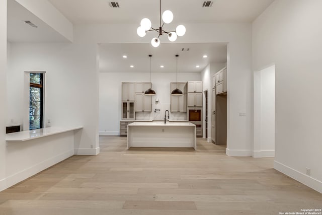 kitchen with an inviting chandelier, hanging light fixtures, sink, and light hardwood / wood-style flooring