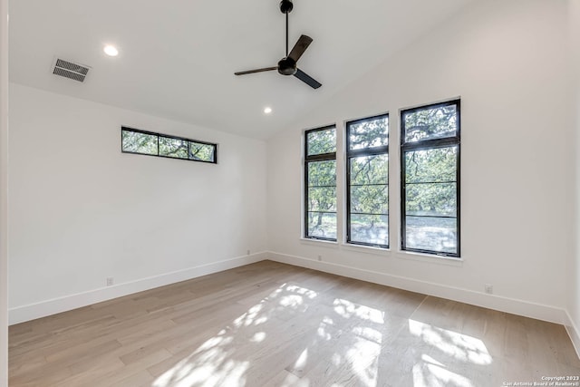 unfurnished room with plenty of natural light, ceiling fan, vaulted ceiling, and light wood-type flooring