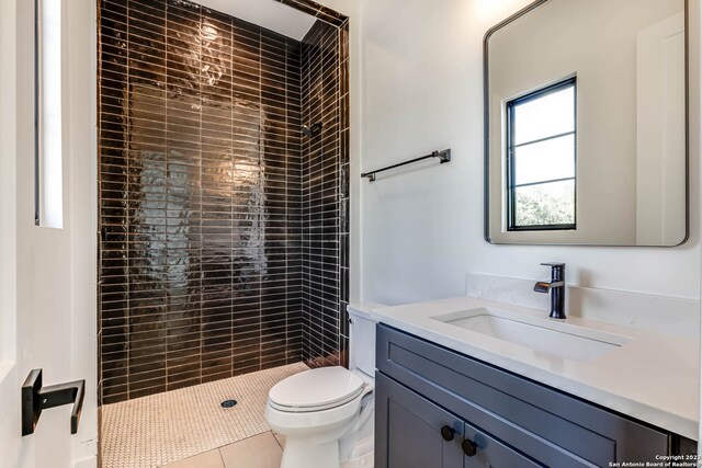 bathroom featuring toilet, a tile shower, and vanity