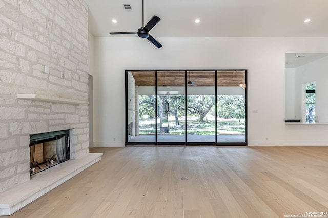 unfurnished living room with a stone fireplace, light hardwood / wood-style floors, and ceiling fan