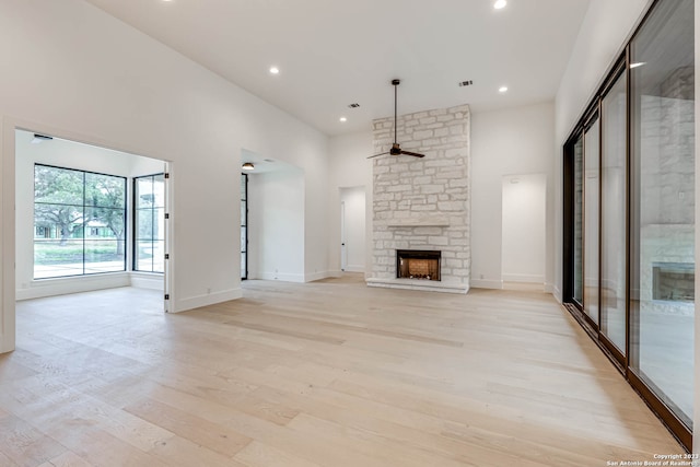 unfurnished living room featuring a fireplace, light hardwood / wood-style floors, and ceiling fan