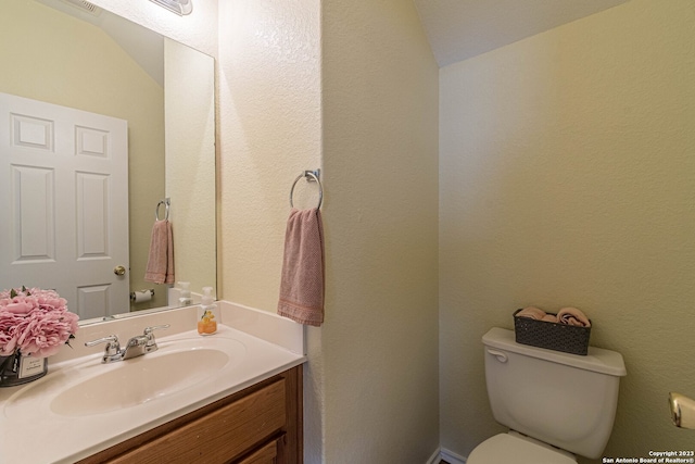 bathroom featuring vanity, vaulted ceiling, and toilet