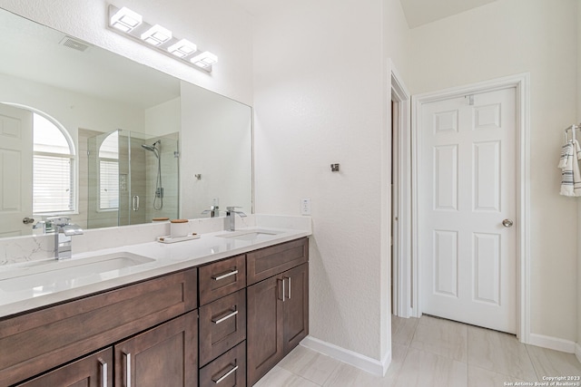 bathroom with a shower with shower door, tile floors, dual sinks, and large vanity