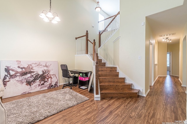 stairs featuring a high ceiling, a notable chandelier, and dark hardwood / wood-style floors