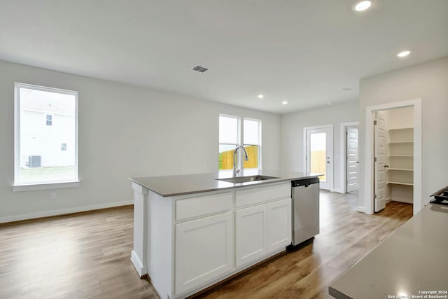 kitchen featuring sink, an island with sink, white cabinets, stainless steel dishwasher, and light wood-type flooring