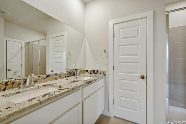 bathroom featuring a shower with door and vanity