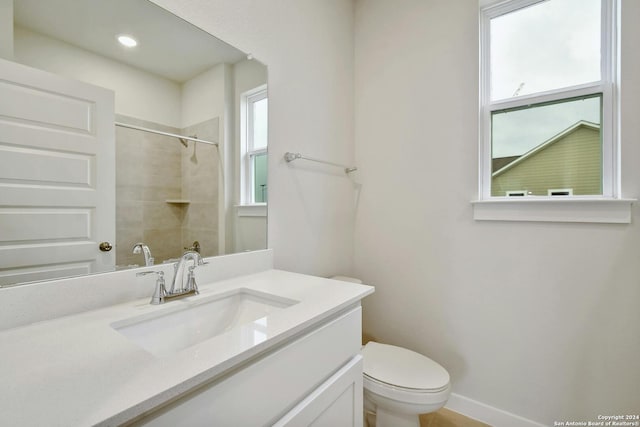 bathroom with vanity, tiled shower, and toilet