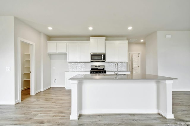 kitchen featuring sink, tasteful backsplash, a center island with sink, appliances with stainless steel finishes, and white cabinets