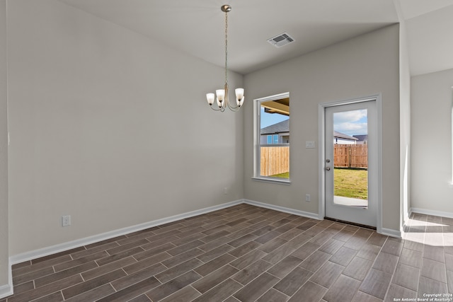 empty room with a notable chandelier and dark hardwood / wood-style flooring