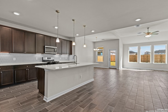 kitchen featuring stainless steel appliances, ceiling fan with notable chandelier, dark brown cabinets, hanging light fixtures, and sink