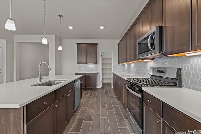 kitchen featuring appliances with stainless steel finishes, backsplash, sink, and pendant lighting