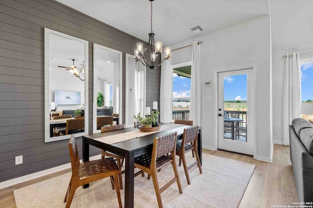 dining room with a healthy amount of sunlight, light hardwood / wood-style flooring, and ceiling fan with notable chandelier