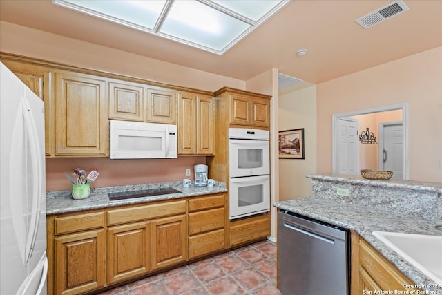 kitchen featuring white appliances, light stone countertops, sink, and light tile floors