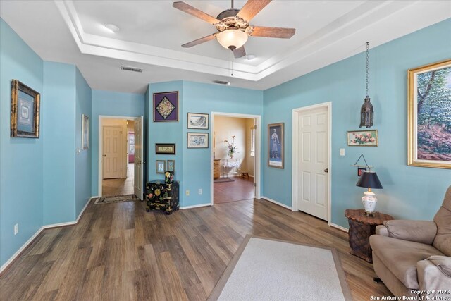 sitting room with ceiling fan, a raised ceiling, and dark hardwood / wood-style floors