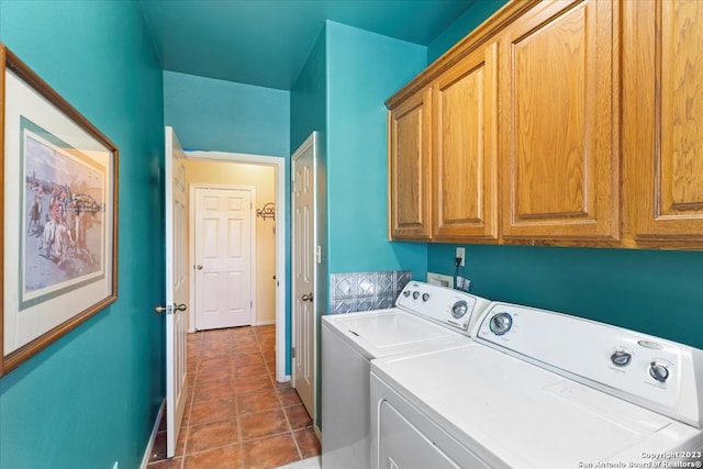 laundry room featuring cabinets, dark tile flooring, and washer and clothes dryer