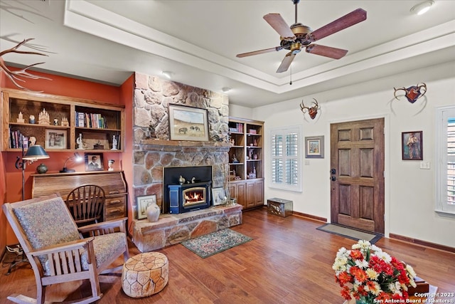 living room with ceiling fan, a fireplace, dark wood-type flooring, and a raised ceiling