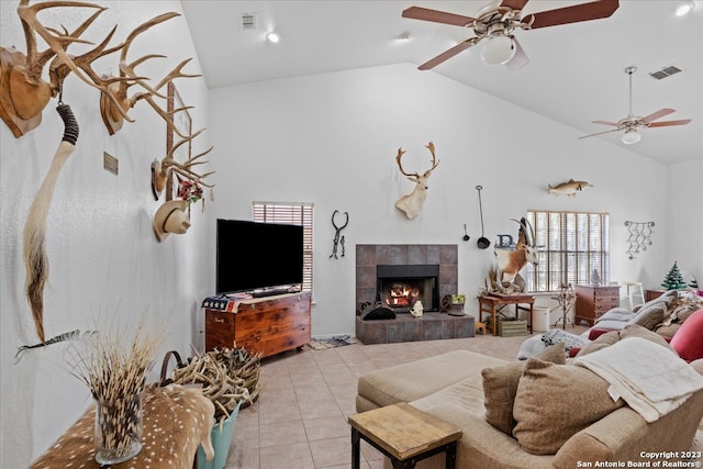 living room with lofted ceiling, ceiling fan, a tile fireplace, and light tile floors