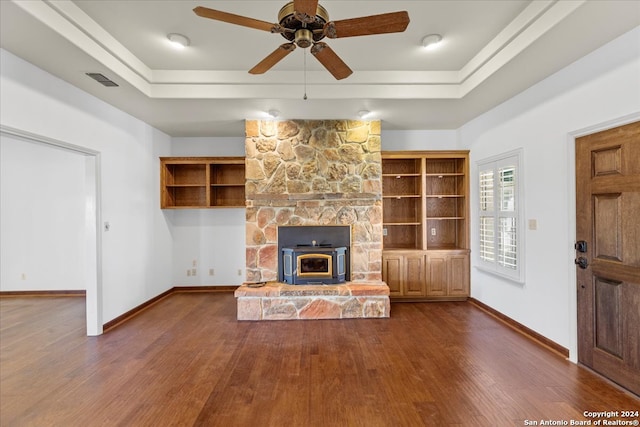 unfurnished living room featuring dark hardwood / wood-style flooring, ceiling fan, a fireplace, and a tray ceiling