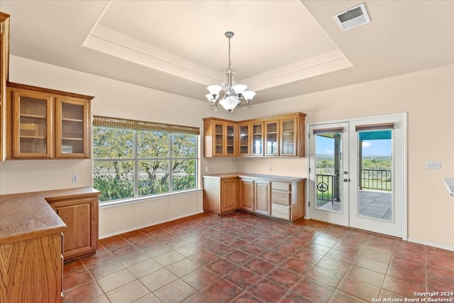 kitchen with french doors, hanging light fixtures, a raised ceiling, a chandelier, and dark tile floors