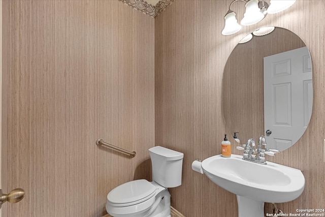 bathroom featuring wood walls, toilet, and sink