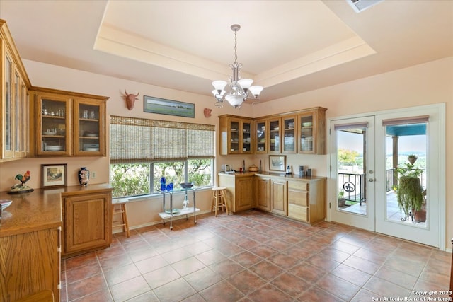 unfurnished office with a tray ceiling, a wealth of natural light, and an inviting chandelier