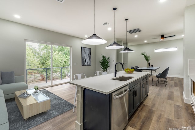 kitchen featuring ceiling fan, dishwasher, sink, pendant lighting, and a kitchen island with sink