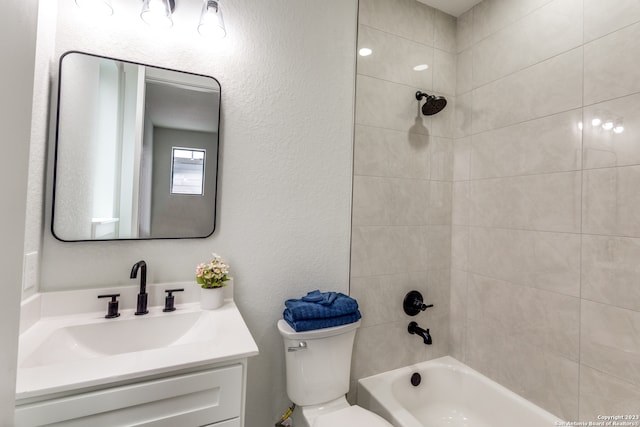 full bathroom with vanity, tiled shower / bath combo, and toilet