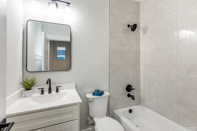 full bathroom featuring vanity, tiled shower / bath combo, and toilet