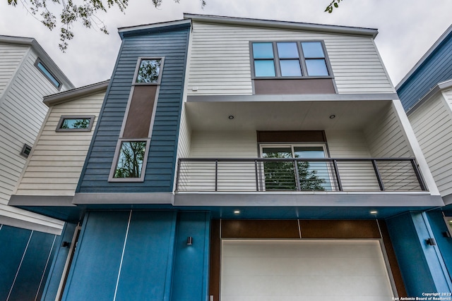 back of property featuring a balcony and a garage