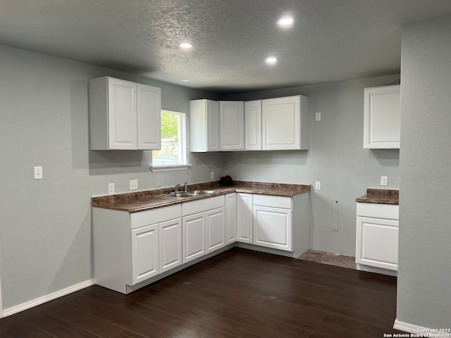 kitchen with white cabinetry, a textured ceiling, dark hardwood / wood-style floors, and sink