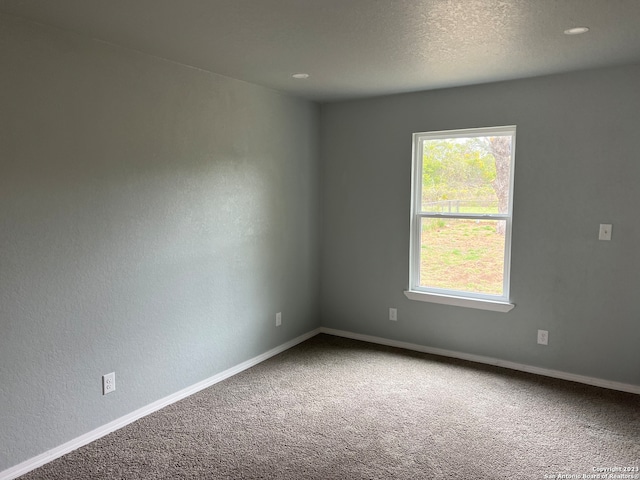 carpeted empty room featuring a textured ceiling