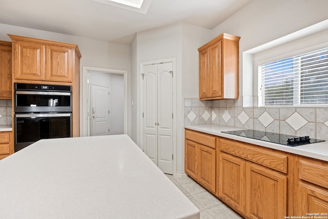 kitchen featuring backsplash, black electric cooktop, double oven, and light tile floors