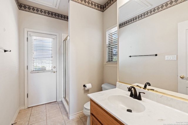 bathroom featuring tile flooring, a shower with door, vanity, and toilet