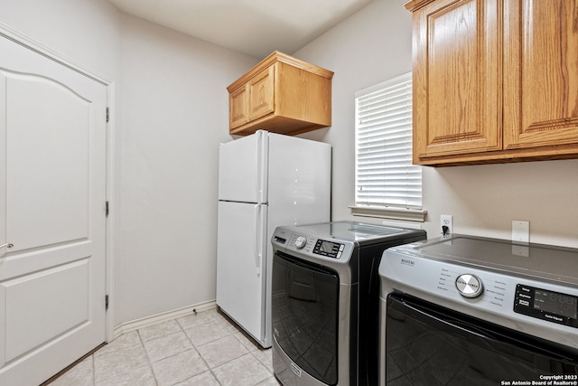 washroom with cabinets, washer and dryer, and light tile floors