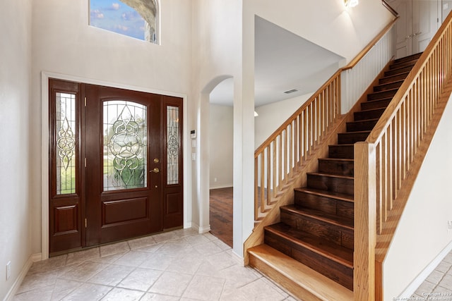 foyer entrance featuring light wood-type flooring and a towering ceiling