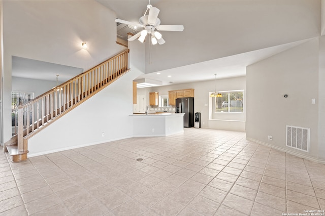 unfurnished living room featuring ceiling fan with notable chandelier, sink, and light tile floors