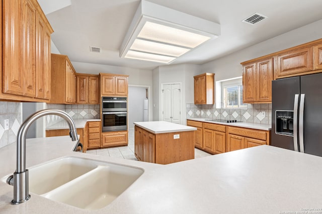 kitchen with sink, appliances with stainless steel finishes, backsplash, and a kitchen island