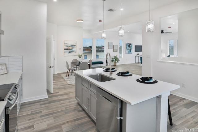 kitchen with hanging light fixtures, appliances with stainless steel finishes, wood-type flooring, sink, and a wealth of natural light