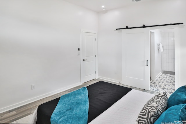 bedroom with a barn door and light hardwood / wood-style floors